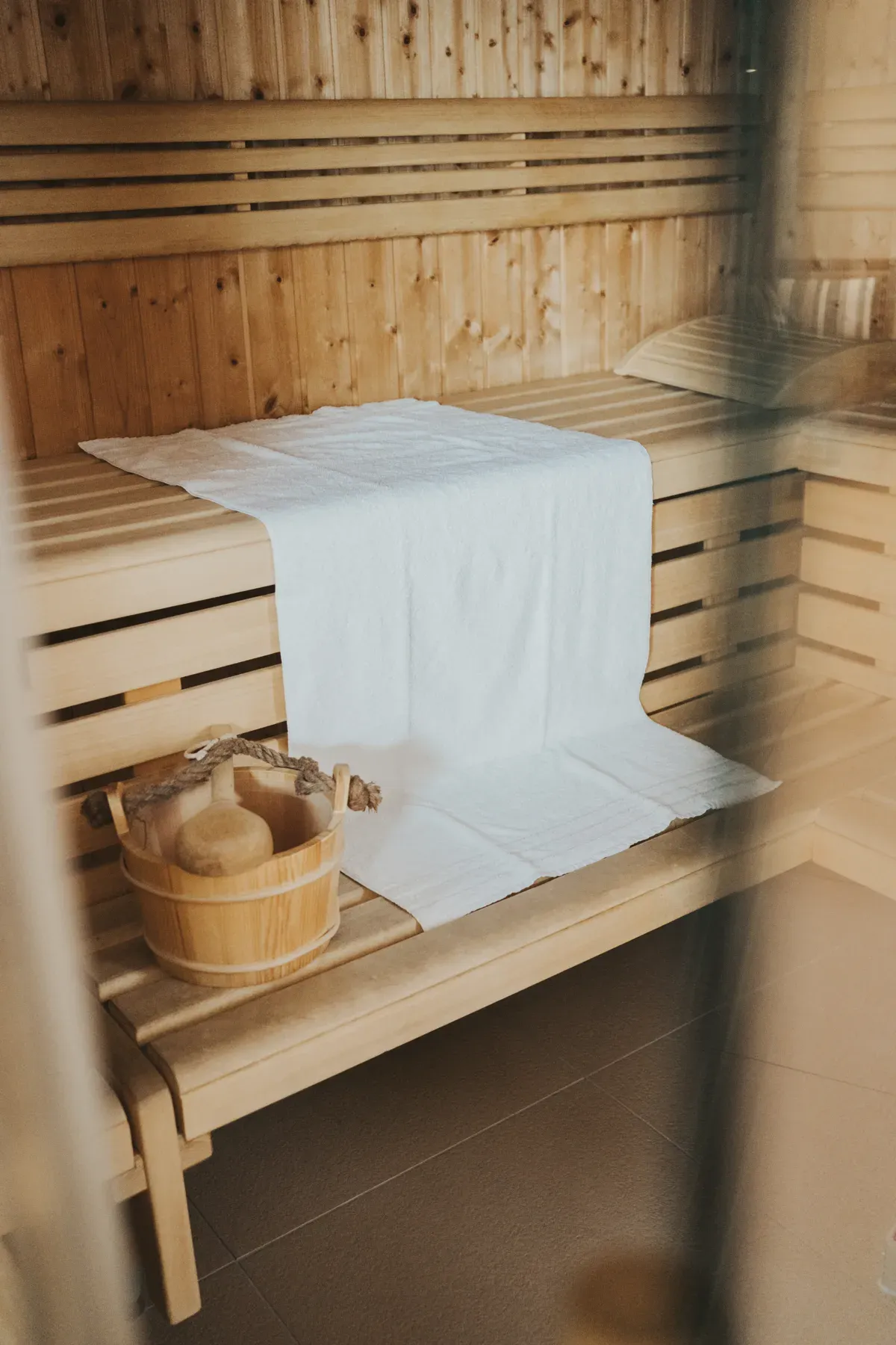 Die Sauna im Sampurna mit Holzbänken, Handtuch und Aufgusskübel